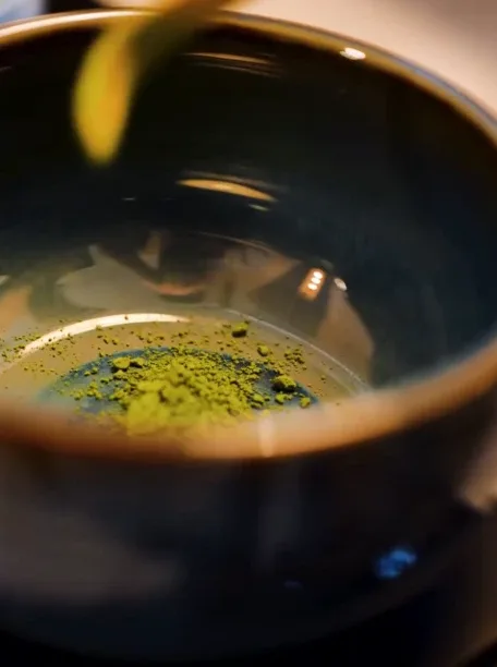Poudre de matcha vert vif au fond d’un bol sombre