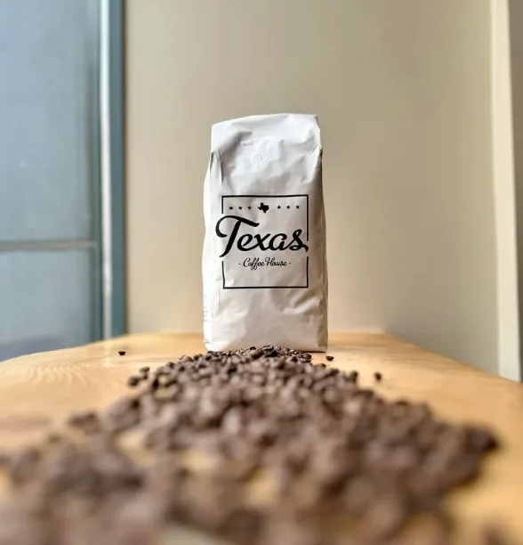 Sachet de café Texas Coffee House sur une table en bois, devant des grains de café